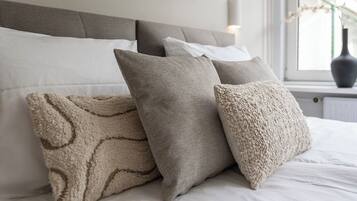 A bed with white bedding and three pillows in a neutral color scheme.