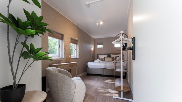 Une chambre à coucher moderne avec un lit, une table de chevet, une chaise et une plante en pot.