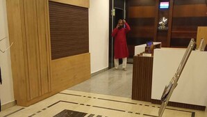 Et område med reception, gulv med mønster, en receptionsdisk og en væg beklædt med træpaneler.