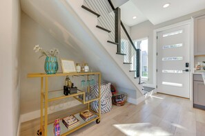 A modern interior with a staircase, a glass display cart, and a door leading to another room. - Walk to Dtwn Shops & Eats: St Augustine Haven! (St. Augustine)
