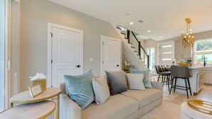 A modern living room with a sofa, a coffee table, and a staircase leading to a kitchen. - Walk to Dtwn Shops & Eats: St Augustine Haven! (St. Augustine)