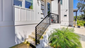 A modern building with a white exterior, a black metal staircase, and a small garden area with green plants. - Walk to Dtwn Shops & Eats: St Augustine Haven! (St. Augustine)