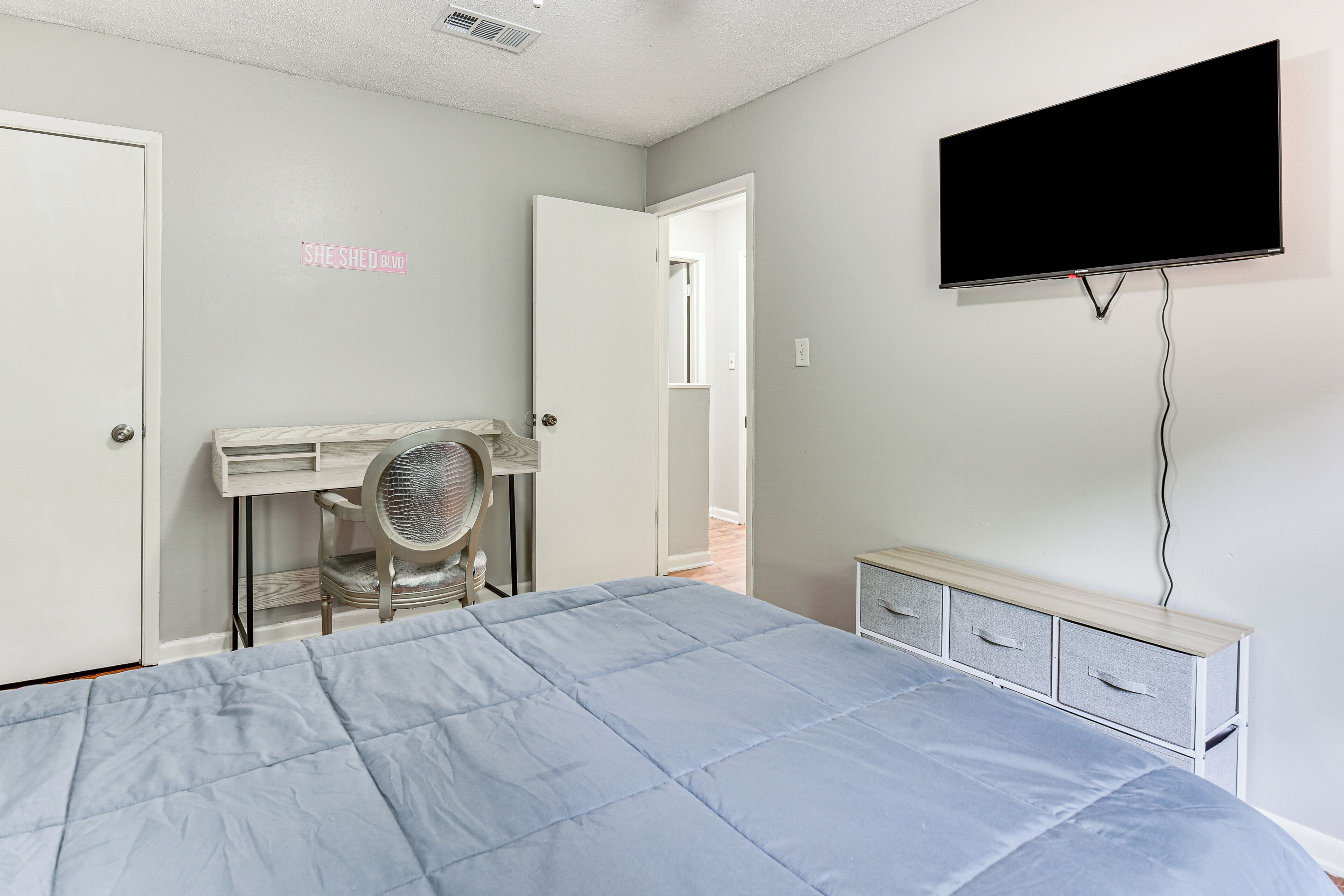 A bedroom with a bed, a desk, a chair, a TV, and a wardrobe.