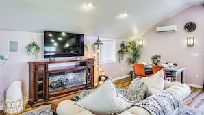 Una sala de estar con chimenea, televisor y comedor con sillas y mesa.