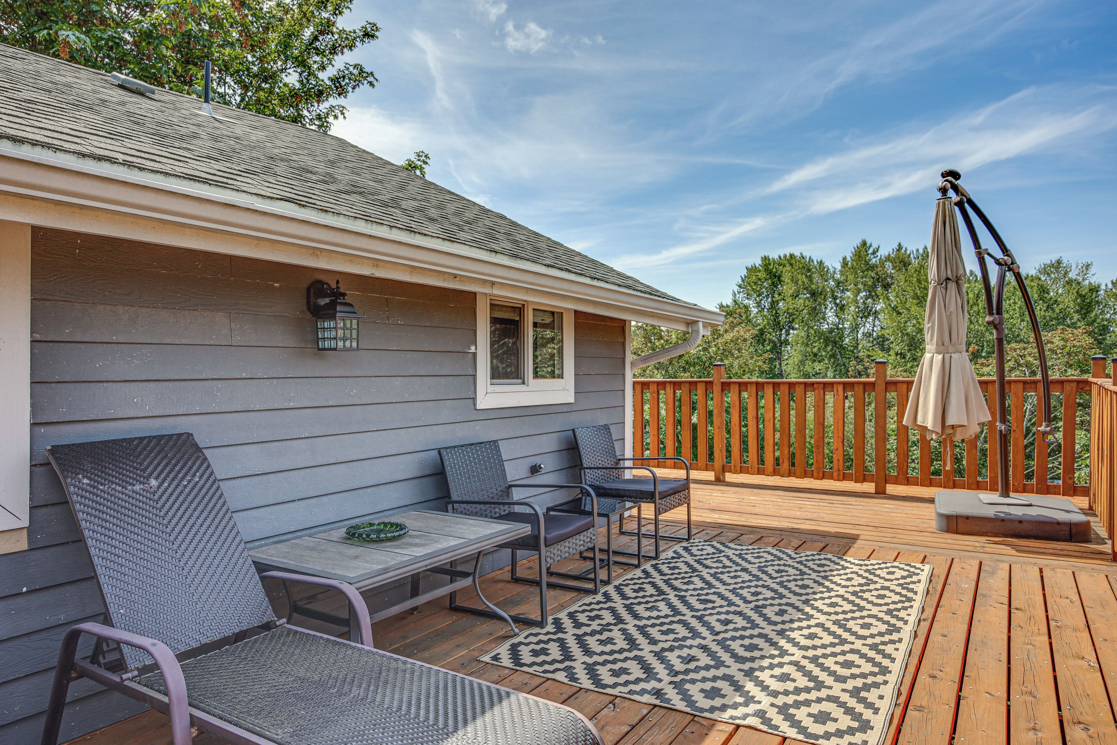 A covered deck with outdoor furniture, a table, and a patterned rug.