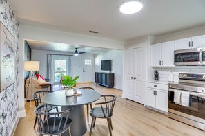 A modern kitchen with white cabinets, a dining area with a round table and chairs, and a ceiling fan. - 1 Mi to Texas Tech: Home w/ Large Outdoor Space! (Lubbock)