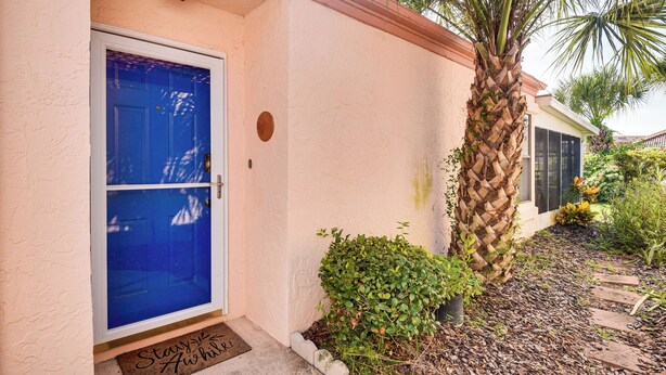 Una casa amb una porta blava, una palmera i un felpí amb la frase 'Stay & Awaken' escrita hi damunt.