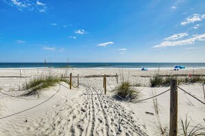 A sandy beach with footprints leading to the water, a wooden fence, and a tent in the distance. - 'wandering Waves!' w/ Private Beach & Pool Access (St. Augustine)