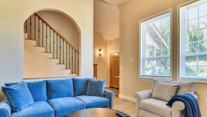 A living room with a blue sofa, a beige armchair, a wooden coffee table, and a staircase with a wooden railing. - Private Outdoor Space 9 Mi to Downtown Vancouver! (Vancouver)