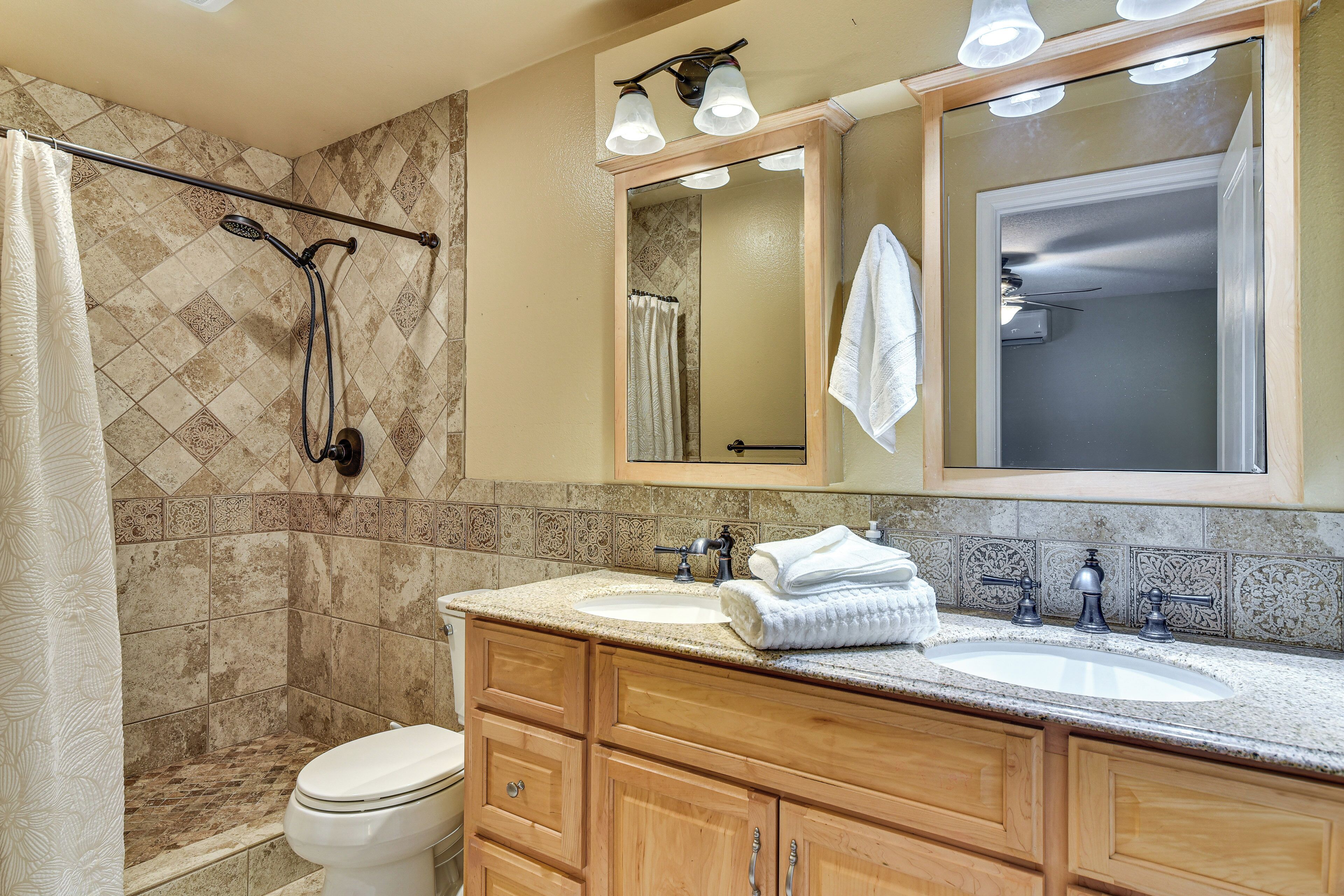 Une salle de bain avec douche, toilettes, un meuble-lavabo et un grand miroir.