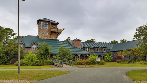 A building with a green roof, brick walls, and a tower-like structure.