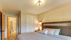 Une chambre à coucher avec un grand lit, une tête de lit en bois, une lampe de chevet et une porte donnant sur une salle de bain.