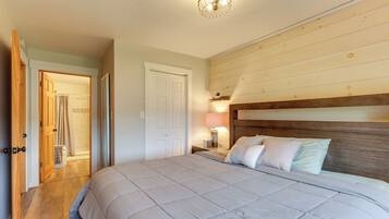 A bedroom with a large bed, wooden headboard, bedside lamp, and a door leading to a bathroom.