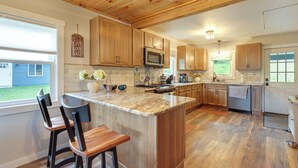 Una cocina con armarios de madera, una isla de granito y vistas al jardín trasero.