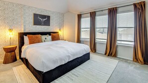 A bedroom with a large bed, two bedside lamps, a ceiling fan, and a window with curtains. - Group-friendly Grand Prairie Home w/ Perks! (Grand Prairie)