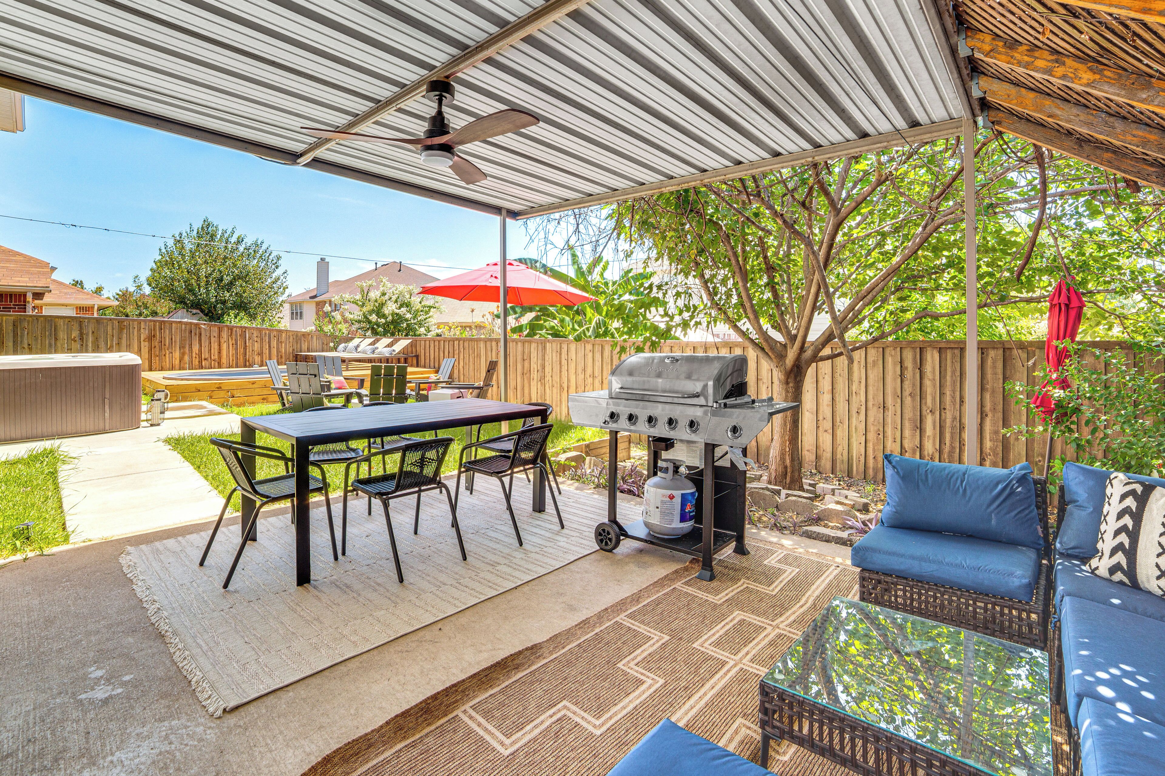 An outdoor patio with a grill, dining table, and chairs.
