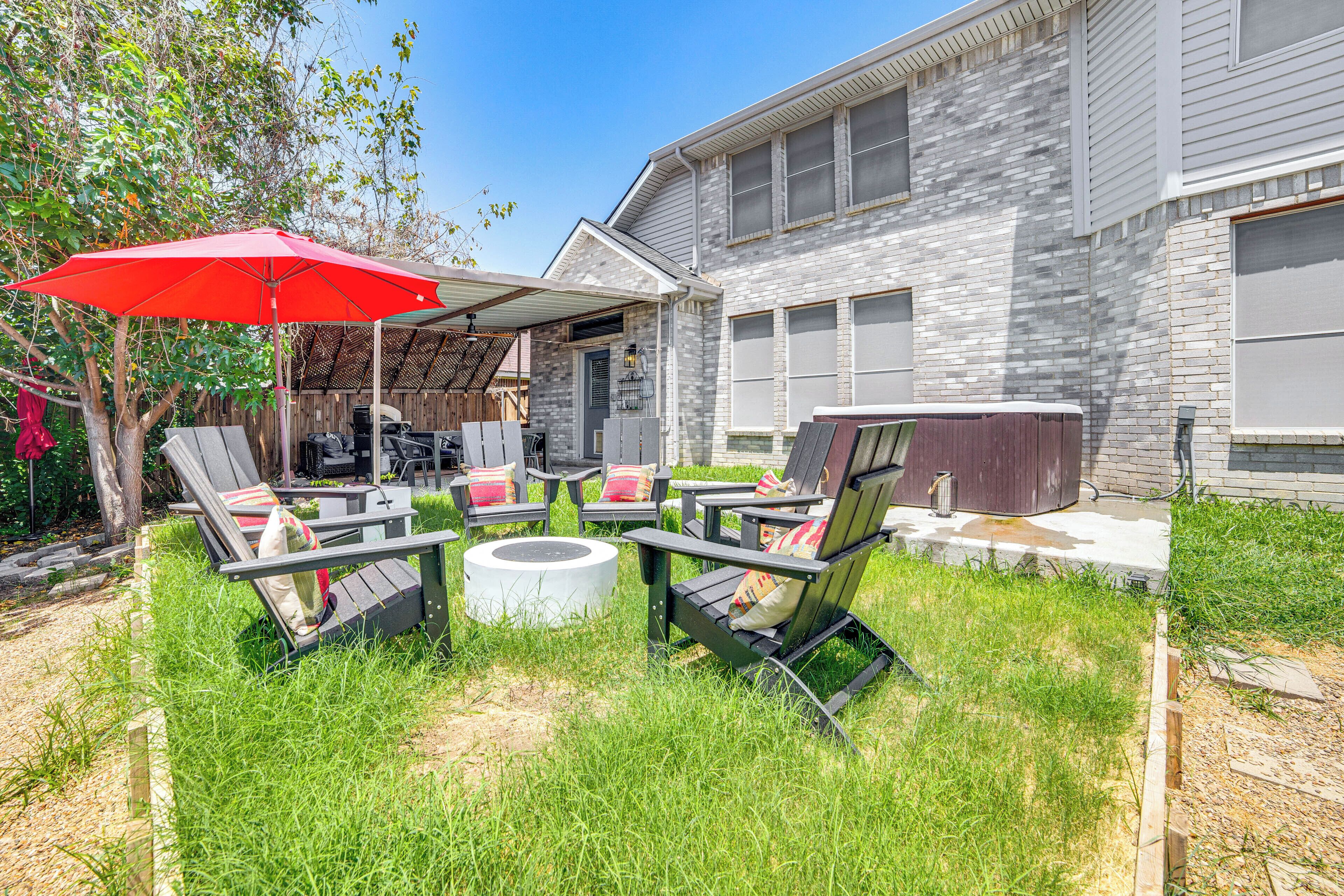 A backyard with a patio area featuring outdoor furniture and a red umbrella.