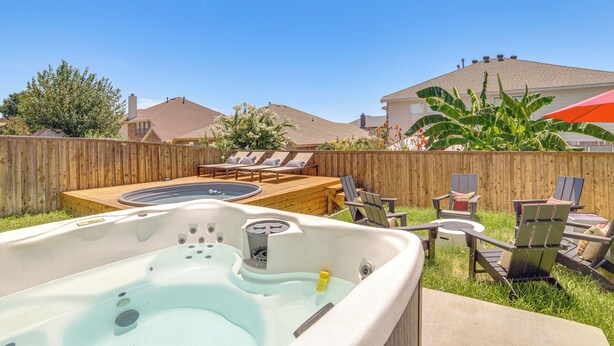 A backyard with a hot tub, lounge chairs, and a wooden deck. - Group-friendly Grand Prairie Home w/ Perks! (Grand Prairie)