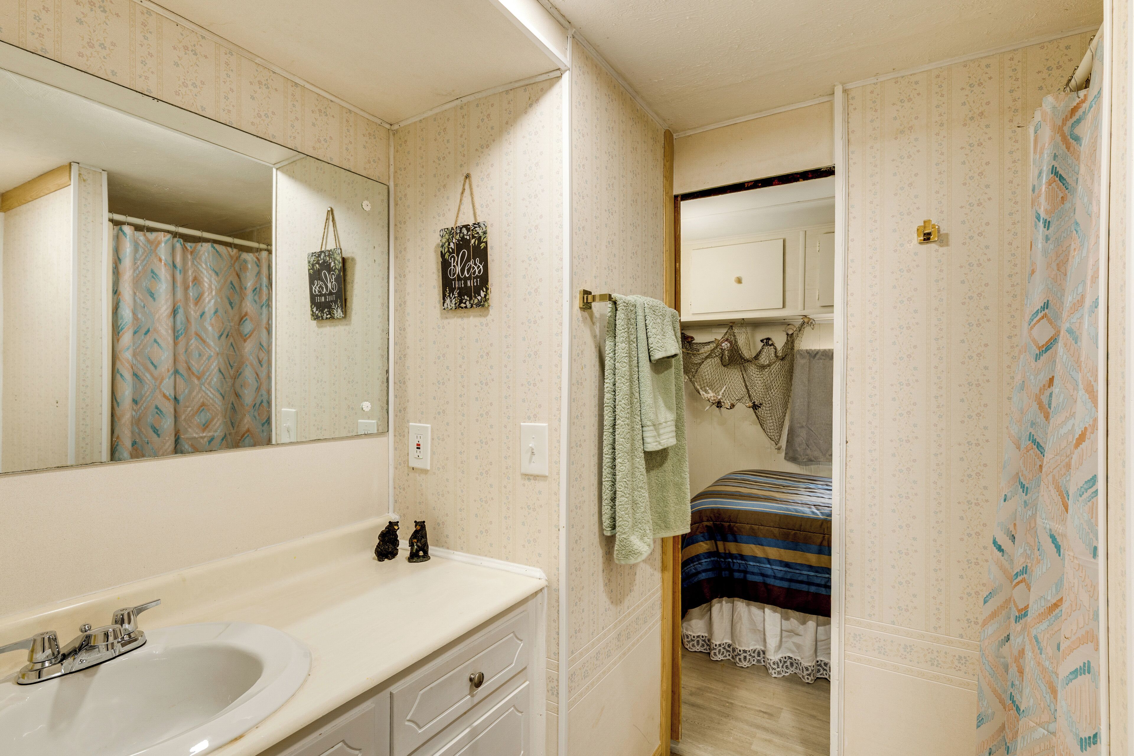 A bathroom with a sink, mirror, and patterned shower curtain.