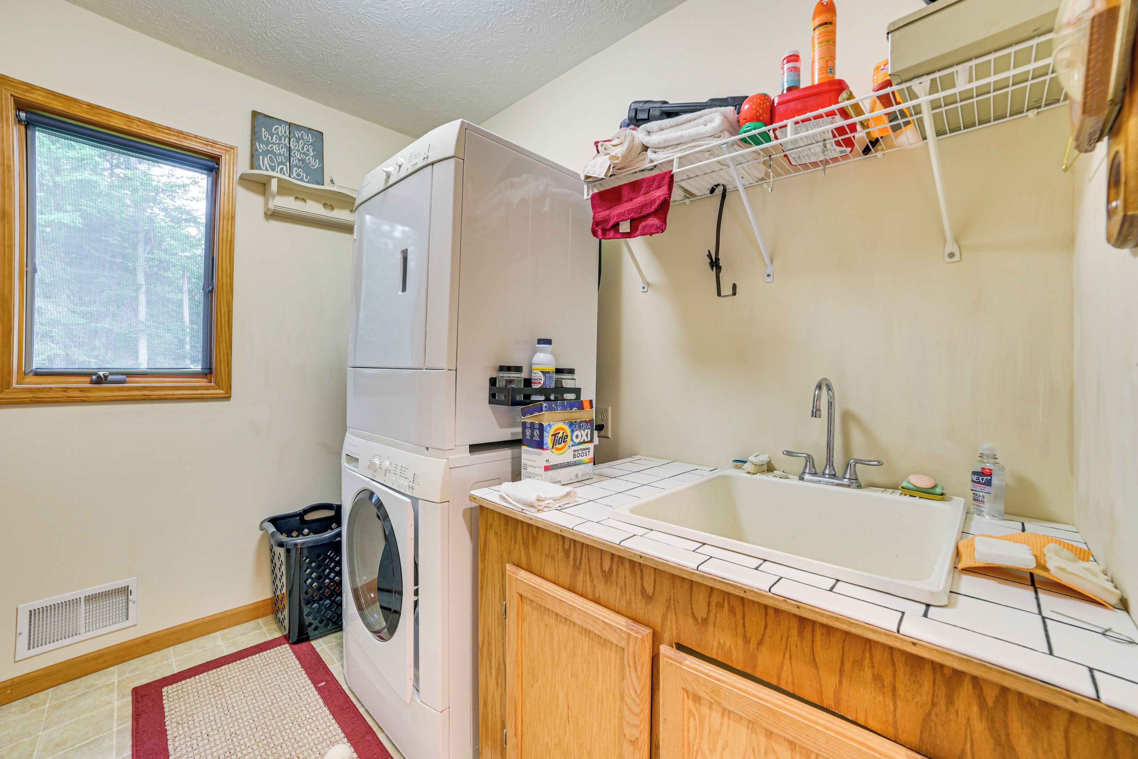 A laundry room with a washing machine, dryer, and a sink with a tiled countertop.