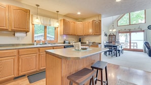A spacious kitchen with wooden cabinets, a central island with stools, and a dining area with a view. - < 2 Mi to Brimley State Park: Lake Superior Home (Brimley)
