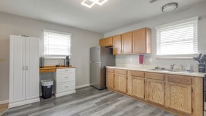 Une cuisine moderne avec des meubles en bois, un réfrigérateur en acier inoxydable et un plan de travail blanc.