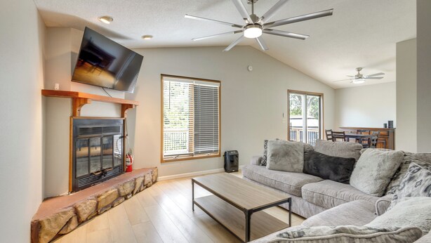 A living room with a fireplace, a sofa, a coffee table, and a television mounted on the wall. - Lakefront Family Home 13 Mi From Gateway Arch! (Granite City)