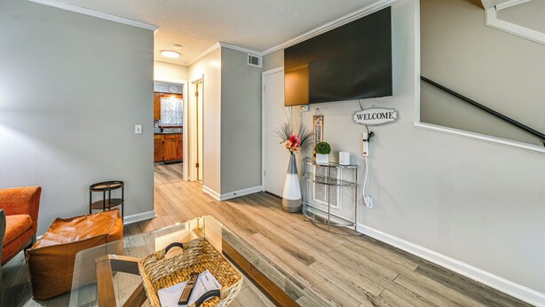 A modern living room with a glass coffee table, a sofa, and a TV mounted on the wall.