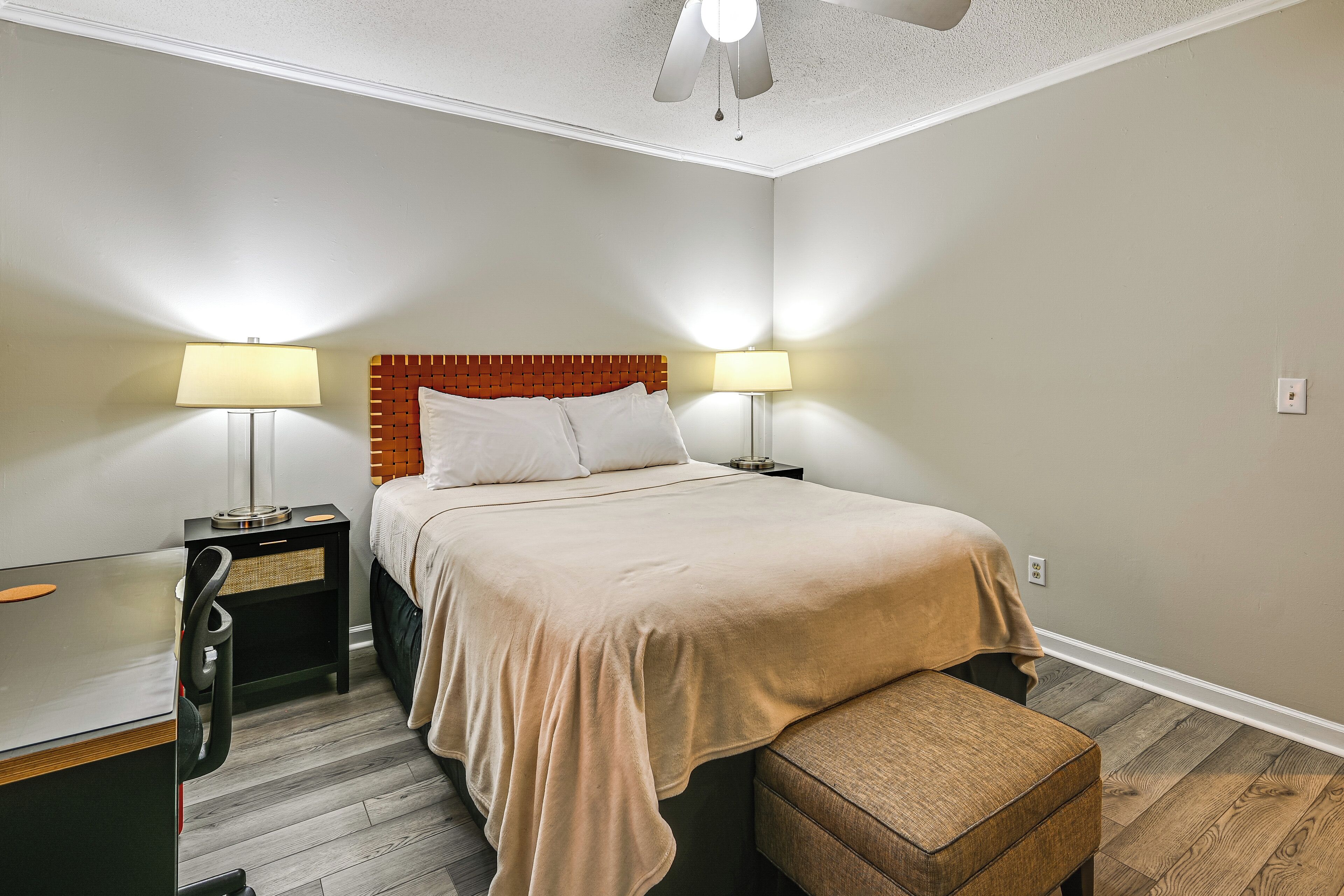 A bedroom with a bed, bedside tables, a desk, and a chair.