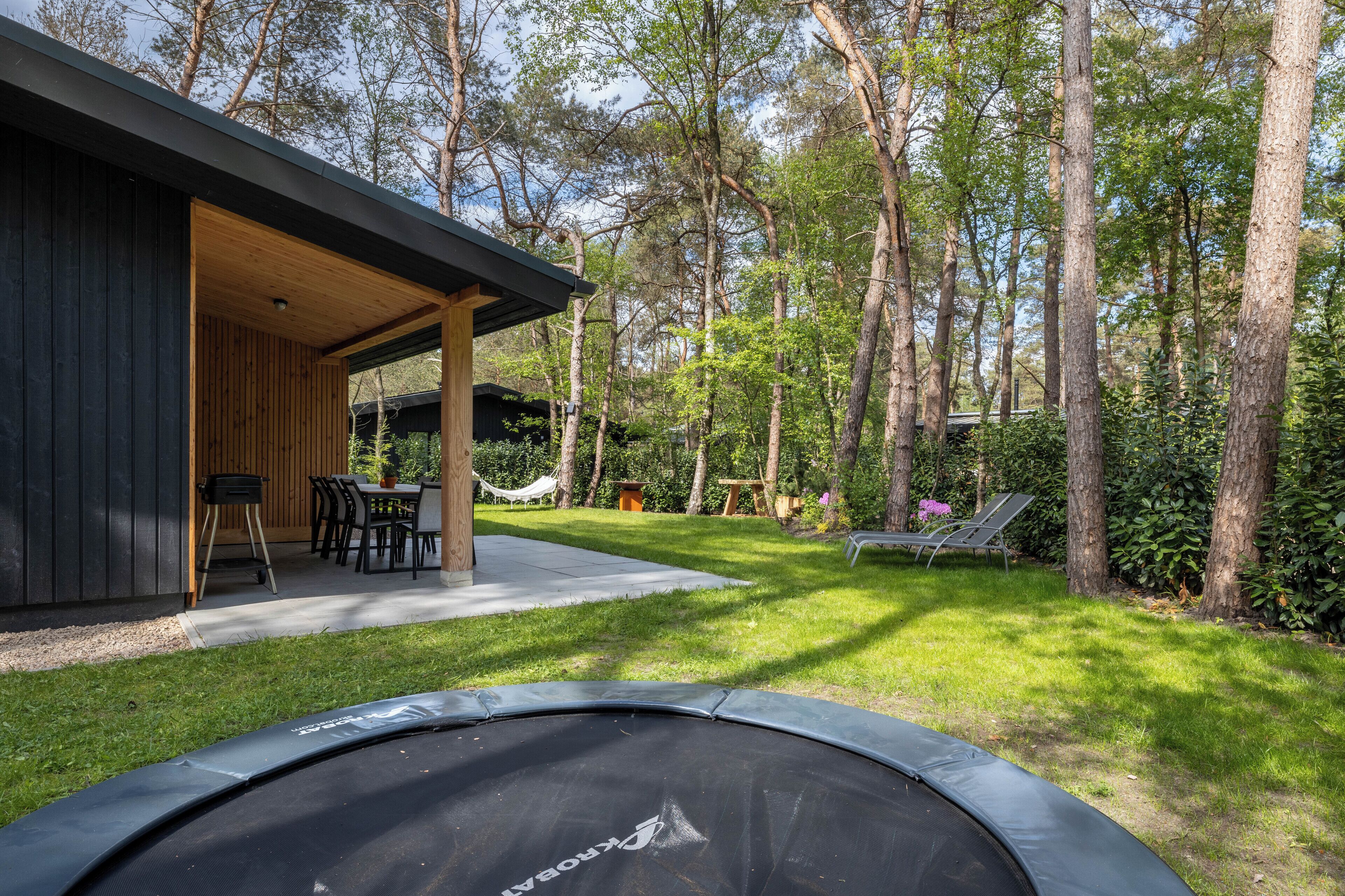 A modern outdoor patio with a trampoline, a wooden deck, and a hammock.