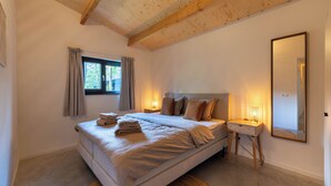 A bedroom with a large bed, bedside tables, a mirror, and a window with curtains. - Geniet samen van de rust en natuur (Giethmen)