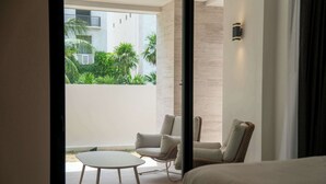A modern hotel room with a balcony, a round table, two chairs, and a bed. - Modern Apt | 4BR | Marina & Beach Access (Cancún)