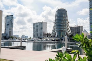 Un puerto deportivo con modernos edificios de gran altura, un paseo marítimo y un cielo despejado.