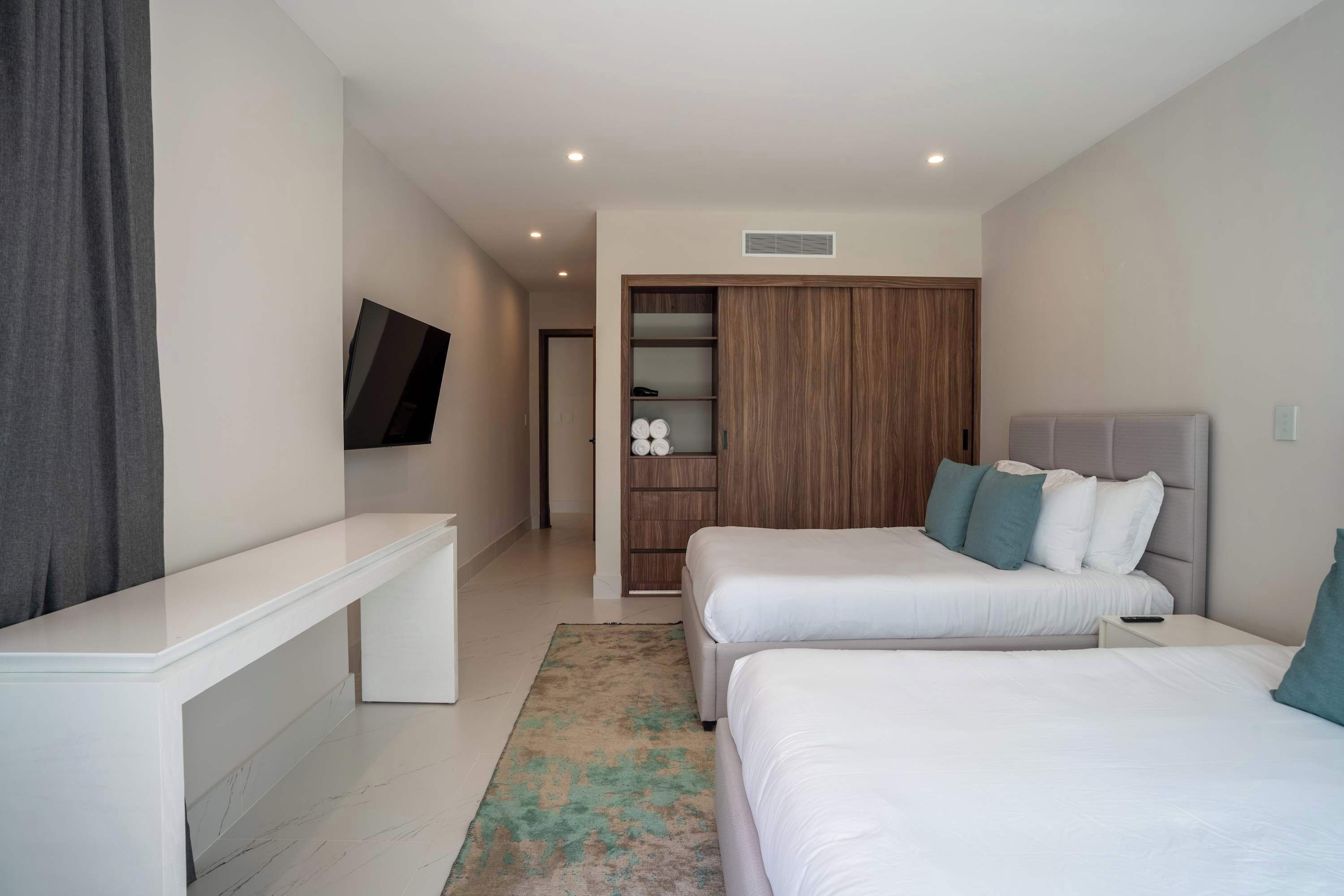 Une chambre d’hôtel moderne dotée d’un grand lit, d’une table de chevet, d’un téléviseur fixé au mur et d’une armoire avec un miroir.
