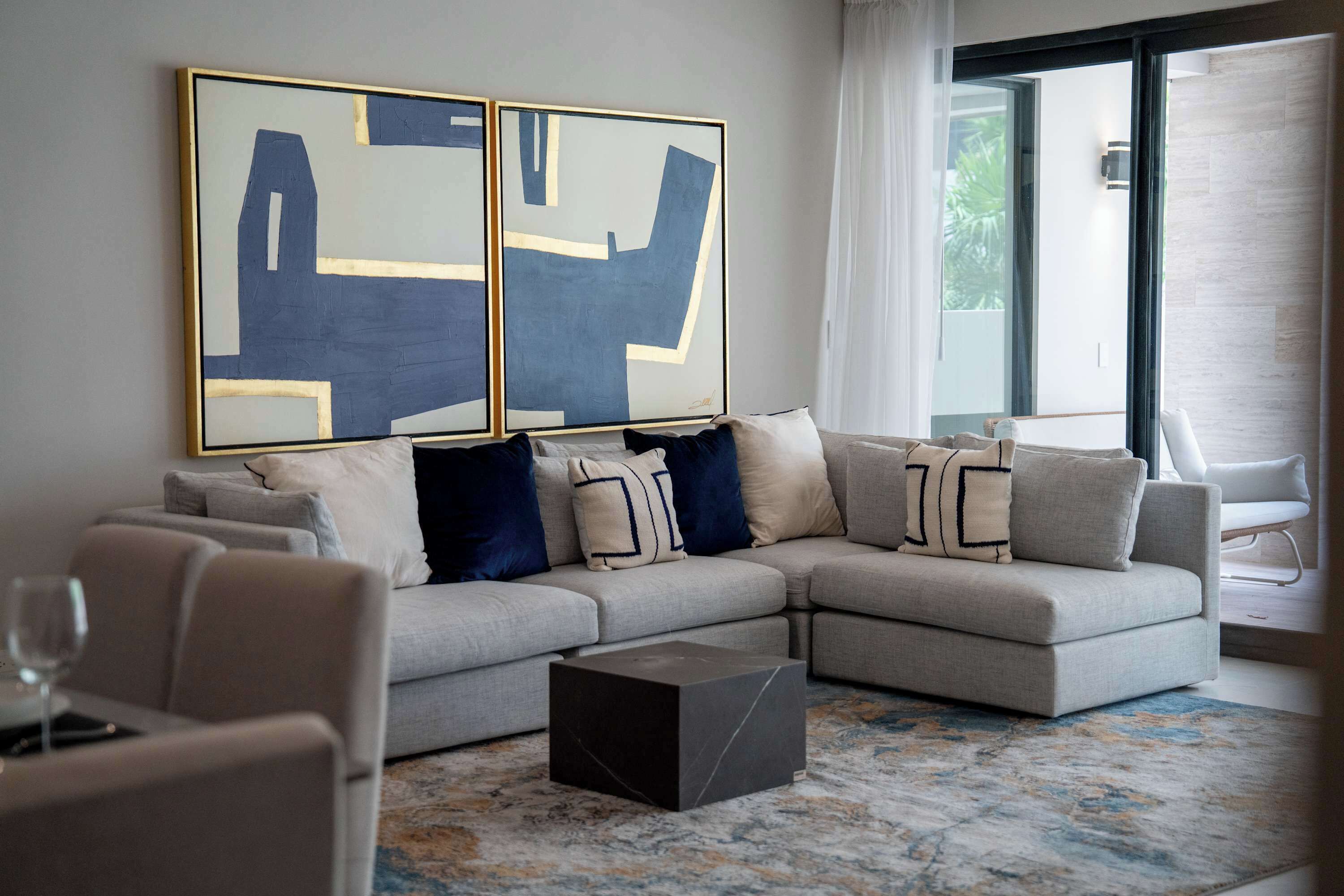 A modern living room with a sectional sofa, a coffee table, and abstract art on the wall.