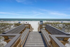 A wooden boardwalk leading to a beach with umbrellas and a sign indicating a no swimming area. - Island Sands #108 – Poolside  Beachfront Getaway! Free Seasonal Beach Service (Fort Walton Beach)
