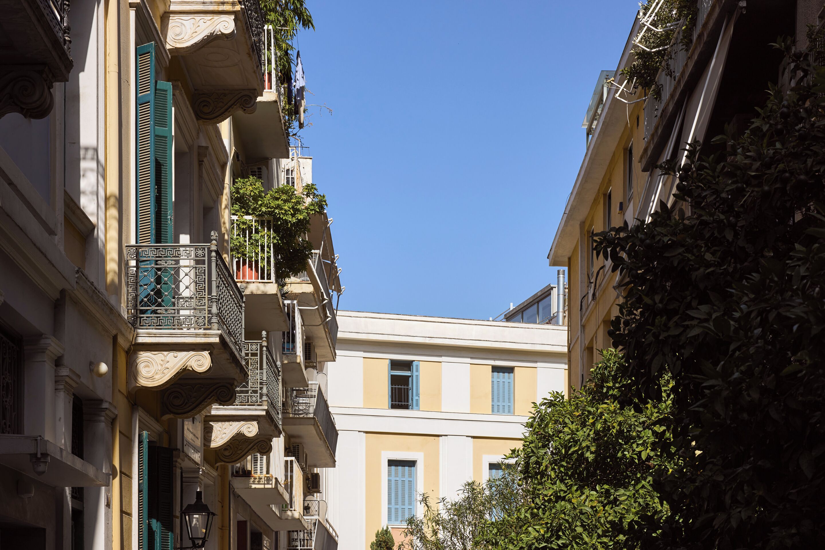 A narrow street with buildings featuring balconies and shutters.