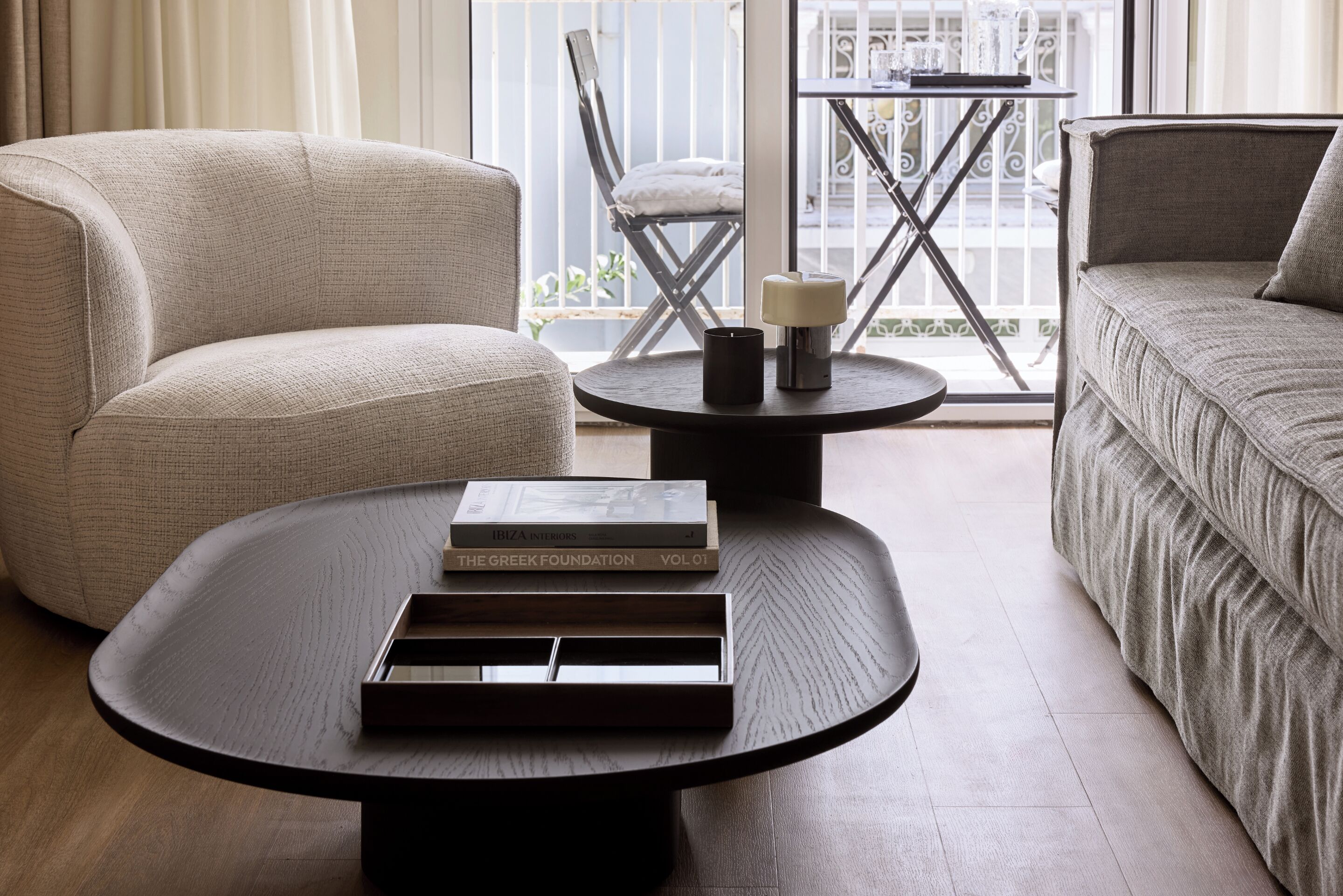 Un salon moderne avec une table basse ronde, un canapé et un fauteuil. Il y a deux livres sur la table.