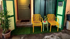 A small, open entrance to a building with a green door and two yellow chairs outside.