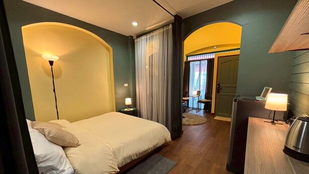 A hotel room with a bed, a desk, a chair, and a lamp.