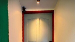 A closed door with a red frame, a doorknob, and a light fixture above it.