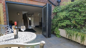 An open patio with a table, a bottle of wine, and a glass. - Sunnyfield Cottage (Coulsdon)