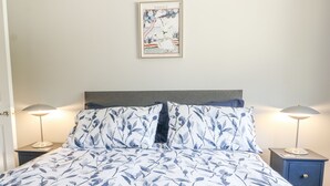 A bed with a floral bedspread, two bedside lamps, and a framed picture on the wall. - Sunnyfield Cottage (Coulsdon)