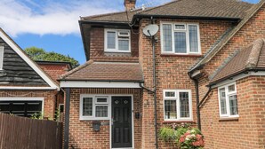 A two-story brick house with a black front door, white-framed windows, and a satellite dish. - Sunnyfield Cottage (Coulsdon)