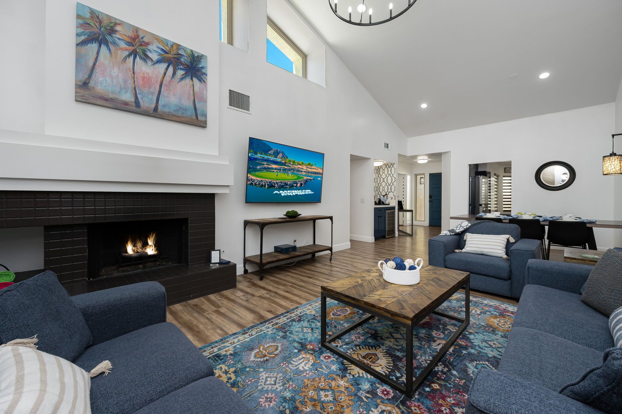 A spacious living room with a fireplace, blue sofas, a coffee table, and a large painting.