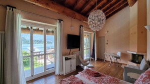 Una habitación con un ventanal grande, una cama, un televisor, una mesa y una chimenea.