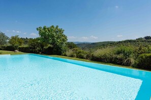 Una piscina cristallina blu circondata da rigogliosa vegetazione e colline sullo sfondo.