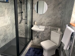A bathroom with a glass-enclosed shower, a sink, a toilet, and a mirror. - 2 Bed-sleeps 4-parking-pets-10 min Walk to Beach (Falmouth)