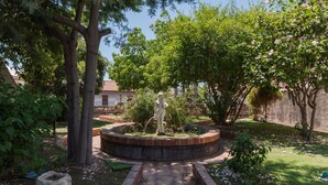 A garden with a central statue, surrounded by trees and shrubs.