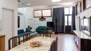A modern living room with a dining table, sofa, and TV.
